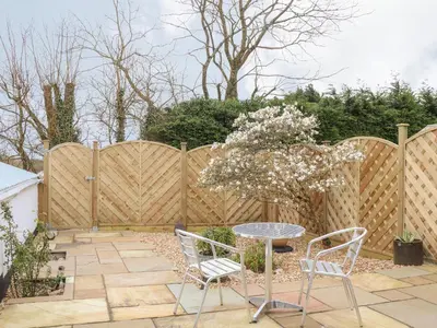 a patio with a table and chairs and a fence at Chycoose in Truro
