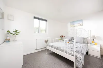 a white bedroom with a white bed and a window at Wheal Jewel- Beautifully Fitted Wooden Lodge Helston Cornwall in Helston