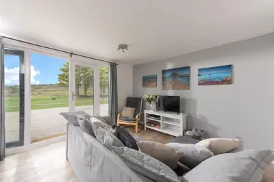 a living room with a couch and a tv at Wheal Jewel- Beautifully Fitted Wooden Lodge Helston Cornwall in Helston