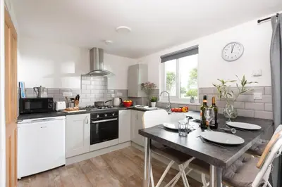 a kitchen with white cabinets and a wooden table at Wheal Jewel- Beautifully Fitted Wooden Lodge Helston Cornwall in Helston