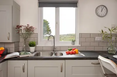 a kitchen counter with a sink and a window at Wheal Amelia- Beautifully Fitted Wooden Lodge Helston Cornwall in Helston