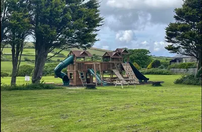a playground with a slide in a field at Wheal Amelia- Beautifully Fitted Wooden Lodge Helston Cornwall in Helston