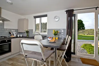 a kitchen with a table and chairs in a kitchen at Wheal Amelia- Beautifully Fitted Wooden Lodge Helston Cornwall in Helston