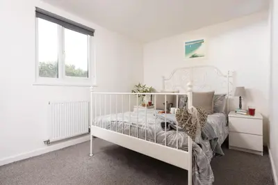 a white bedroom with a white bed and a window at Wheal Prosper- Beautifully Fitted Wooden Lodge Helston Cornwall in Helston