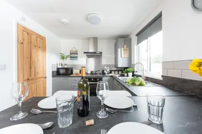 a kitchen with a table with glasses and a bottle of wine at Wheal Prosper- Beautifully Fitted Wooden Lodge Helston Cornwall in Helston