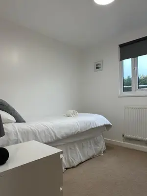 a white bedroom with a bed and a window at Wheal Prosper- Beautifully Fitted Wooden Lodge Helston Cornwall in Helston