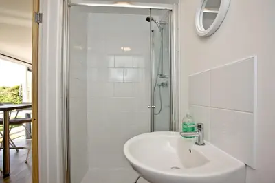 a white bathroom with a sink and a shower at Wheal Prosper- Beautifully Fitted Wooden Lodge Helston Cornwall in Helston