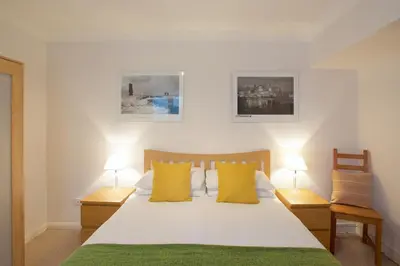 a bedroom with a bed with yellow pillows and two lamps at Beach View in St Ives