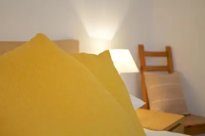 a pile of yellow pillows on a bed with a chair at Beach View in St Ives