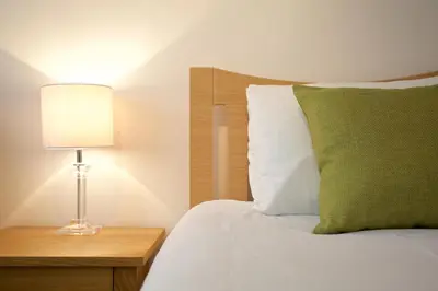 a bedroom with a bed with a green pillow and a lamp at Beach View in St Ives