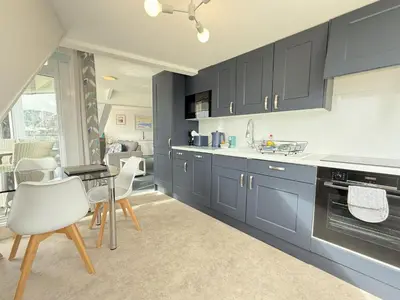a kitchen with blue cabinets and a table and chairs at Crows Nest - panoramic views of St Ives harbour in St Ives