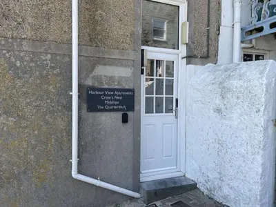 a white door with a sign on the side of a building at Crows Nest - panoramic views of St Ives harbour in St Ives