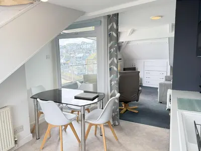 a dining room with a table and chairs and a window at Crows Nest - panoramic views of St Ives harbour in St Ives