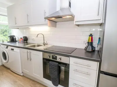 a kitchen with white cabinets and a sink and a dishwasher at The Poop Deck in Helston