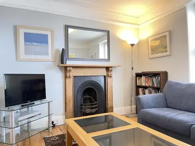 a living room with a couch and a mirror at 37 Trenwith Place, charming family home & garden! in St Ives