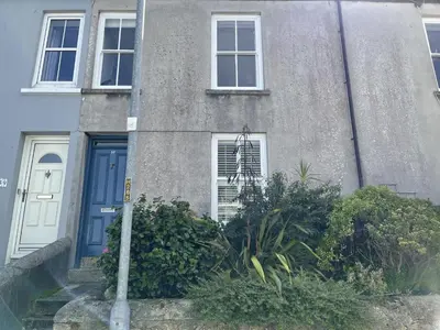 a house with a blue door and some bushes at 37 Trenwith Place, charming family home & garden! in St Ives