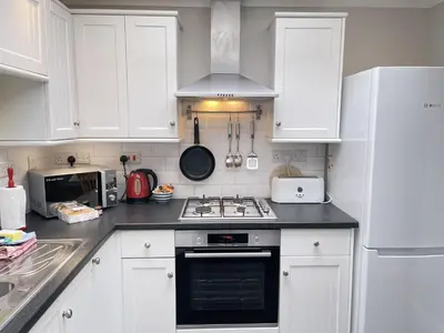 a kitchen with white cabinets and a stove top oven at 37 Trenwith Place, charming family home & garden! in St Ives