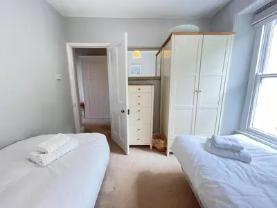 a bedroom with two white beds and a window at 37 Trenwith Place, charming family home & garden! in St Ives