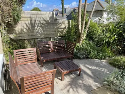 two wooden benches and a table in a garden at Porth House, with south facing courtyard garden! in St Ives