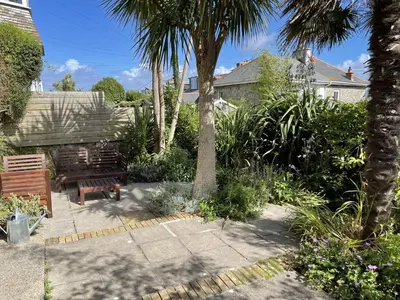a garden with a bench and palm trees at Porth House, with south facing courtyard garden! in St Ives