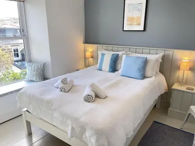 a bedroom with a large white bed with blue pillows at Porth House, with south facing courtyard garden! in St Ives