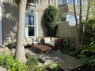 a patio with two chairs and a table and a bench at Porth House, with south facing courtyard garden! in St Ives