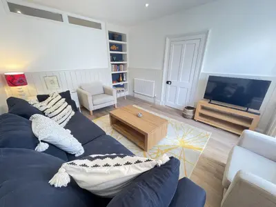 a living room with a blue couch and a tv at Porth House, with south facing courtyard garden! in St Ives