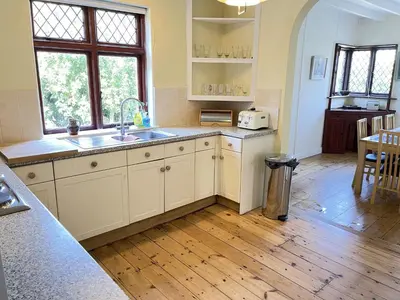 a kitchen with white cabinets and a wooden floor at Stratton Vow - a true 1920s Arts and Crafts house! in St Ives