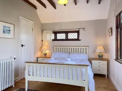 a bedroom with a white bed with two night stands at Stratton Vow - a true 1920s Arts and Crafts house! in St Ives
