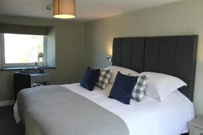 a bedroom with a large white bed with blue pillows at The Five Pilchards Inn in Helston