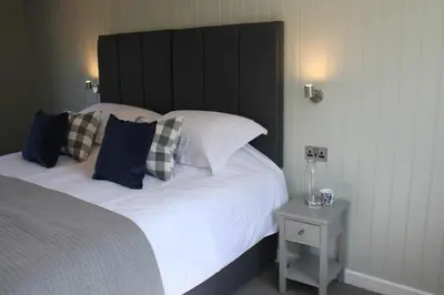 a bedroom with a large bed with a black headboard at The Five Pilchards Inn in Helston