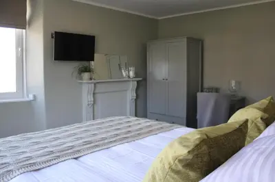 a bedroom with a bed with a television on the wall at The Five Pilchards Inn in Helston