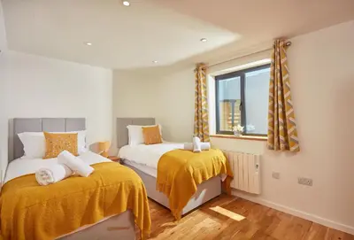a bedroom with two beds and a window at The Larches in St. Agnes
