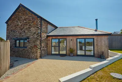 a brick house with glass doors and a patio at The Larches in St. Agnes