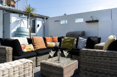 a patio with a couch and a table with wine glasses at Island Wastrel in St Ives
