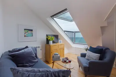 a living room with two blue couches and a window at Little Gem in St Ives