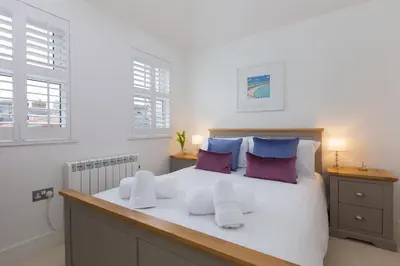 a bedroom with a large white bed with purple pillows at Little Gem in St Ives
