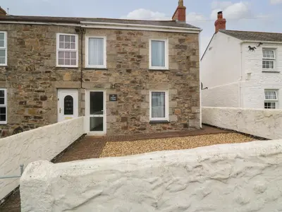 a brick house with a stone wall in front of it at Nappers Cottage in Hayle