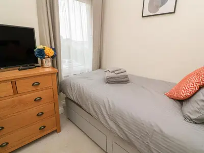 a bedroom with a bed and a dresser with a television at Nappers Cottage in Hayle