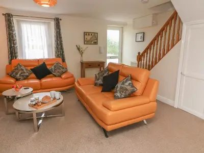 a living room with two orange couches and a staircase at Nappers Cottage in Hayle
