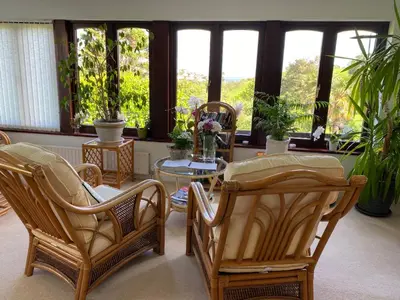 a room with chairs and a table and windows at Kerryanna Country House Bed and Breakfast in Mevagissey