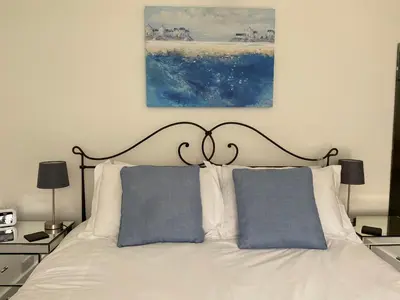 a white bed with two blue pillows on it at Kerryanna Country House Bed and Breakfast in Mevagissey