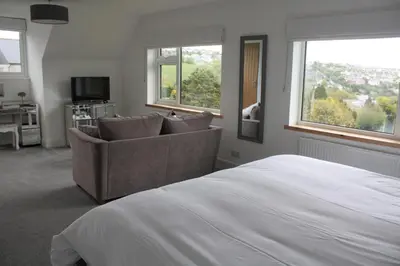 a bedroom with a bed and a couch and windows at Kerryanna Country House Bed and Breakfast in Mevagissey