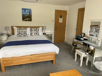 a bedroom with a large bed and a desk at Kerryanna Country House Bed and Breakfast in Mevagissey