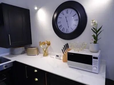 a kitchen counter with a microwave and a clock on the wall at Beachside Apartment in Carbis Bay