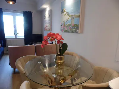 a glass table with a vase with red flowers on it at Beachside Apartment in Carbis Bay
