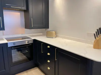 a kitchen with black cabinets and white counter tops at Beachside Apartment in Carbis Bay