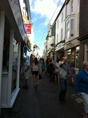 a group of people walking down a street with buildings at Beachside Apartment in Carbis Bay
