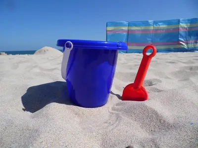 a blue plastic cup and a red shovel in the sand at Beachside Apartment in Carbis Bay