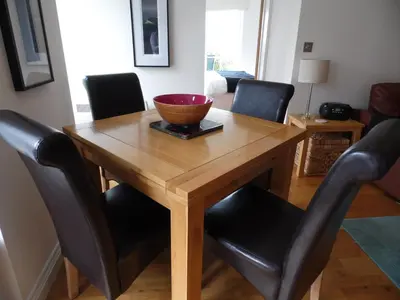 a wooden table with black chairs and a bowl on top at Seaside Apartment in Carbis Bay